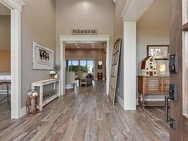 Farmhouse style entryway with wood floors, neutral walls, and decor. A view into the living room.