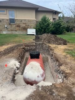 Underground septic tank partially buried, construction site near a house.