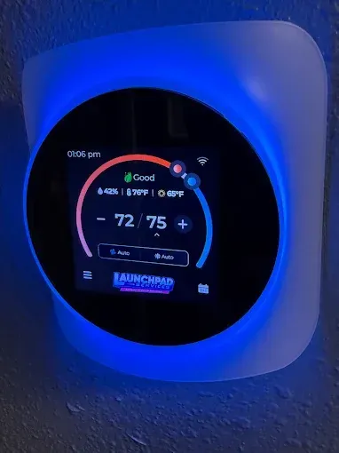 Round blue-lit digital thermostat on a wall, showing 72°F and “Good” status.
