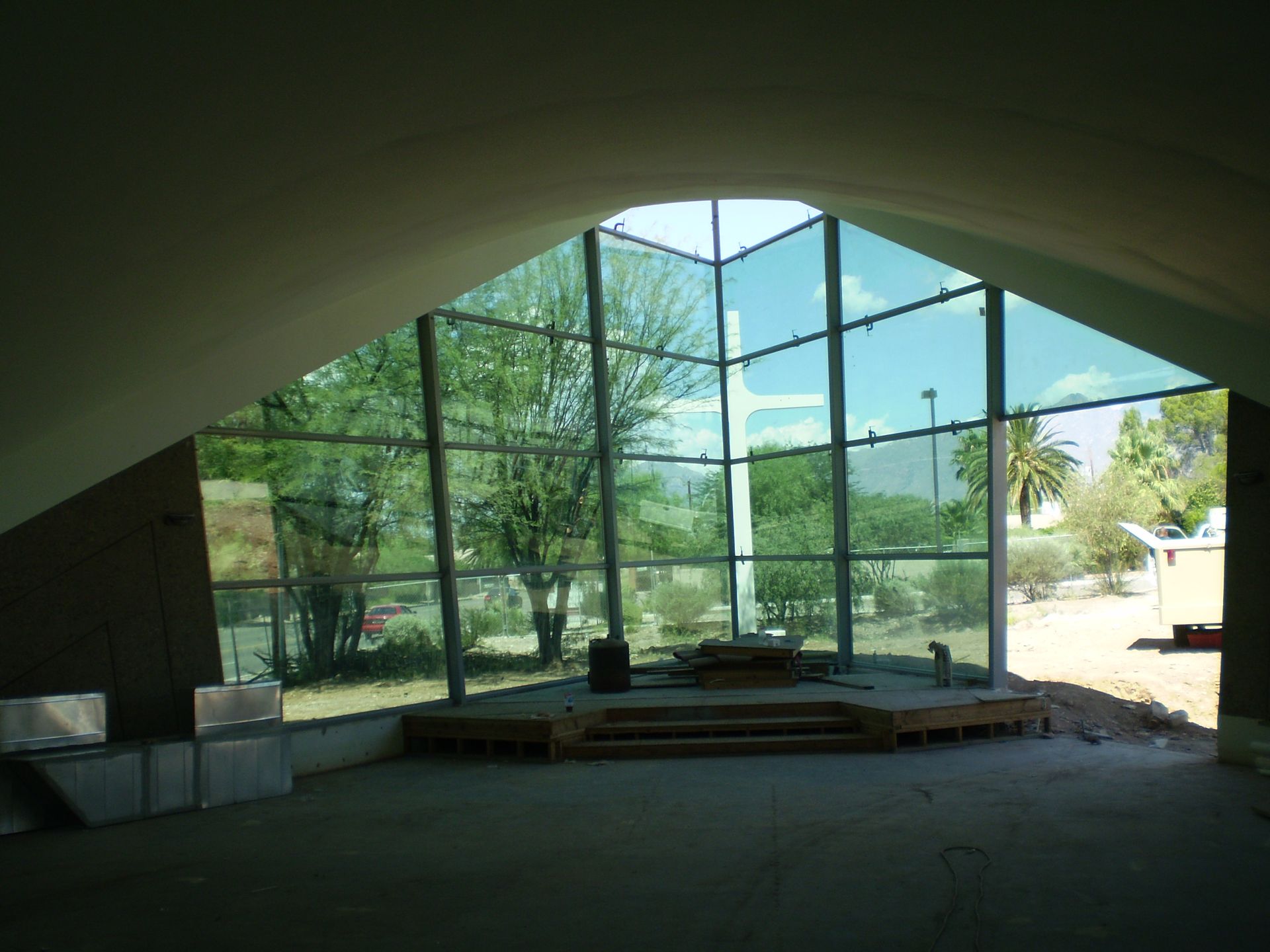 Interior view of a modern building with large angled windows overlooking a green outdoor area.