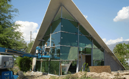 Modern building with triangular glass facade; blue lift in front.