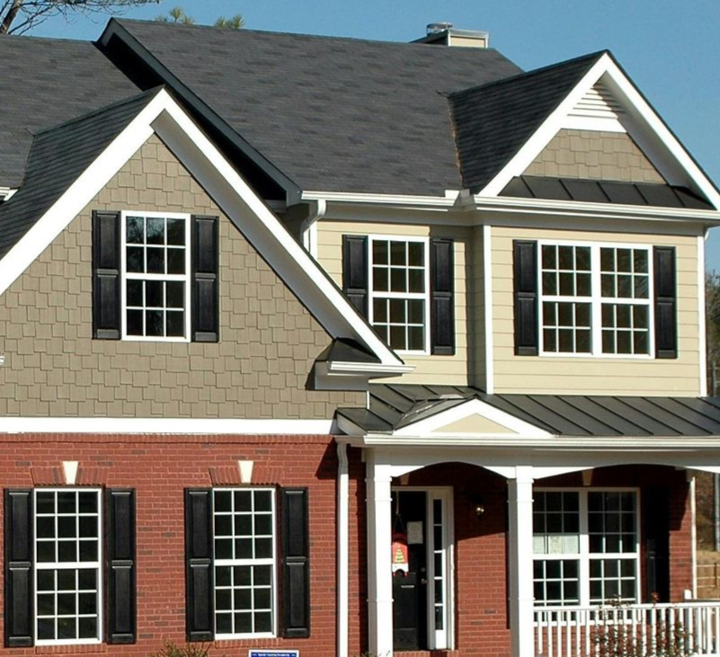Two-story house with red brick and tan siding, black shutters, and dark gray roof.