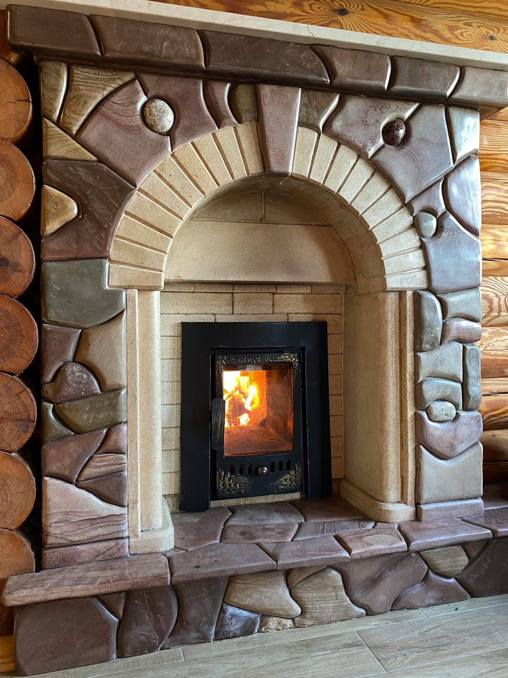 Stone fireplace with arched opening, fire burning inside.
