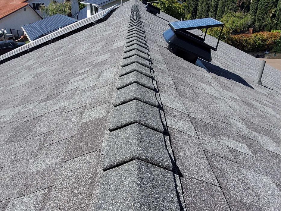 Gray shingle roof with a central ridge capped by angled shingles.