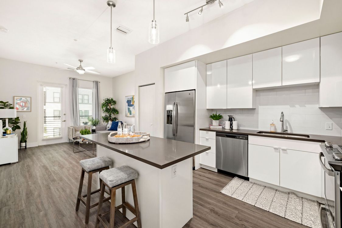 A kitchen with white cabinets and stainless steel appliances and a large island.