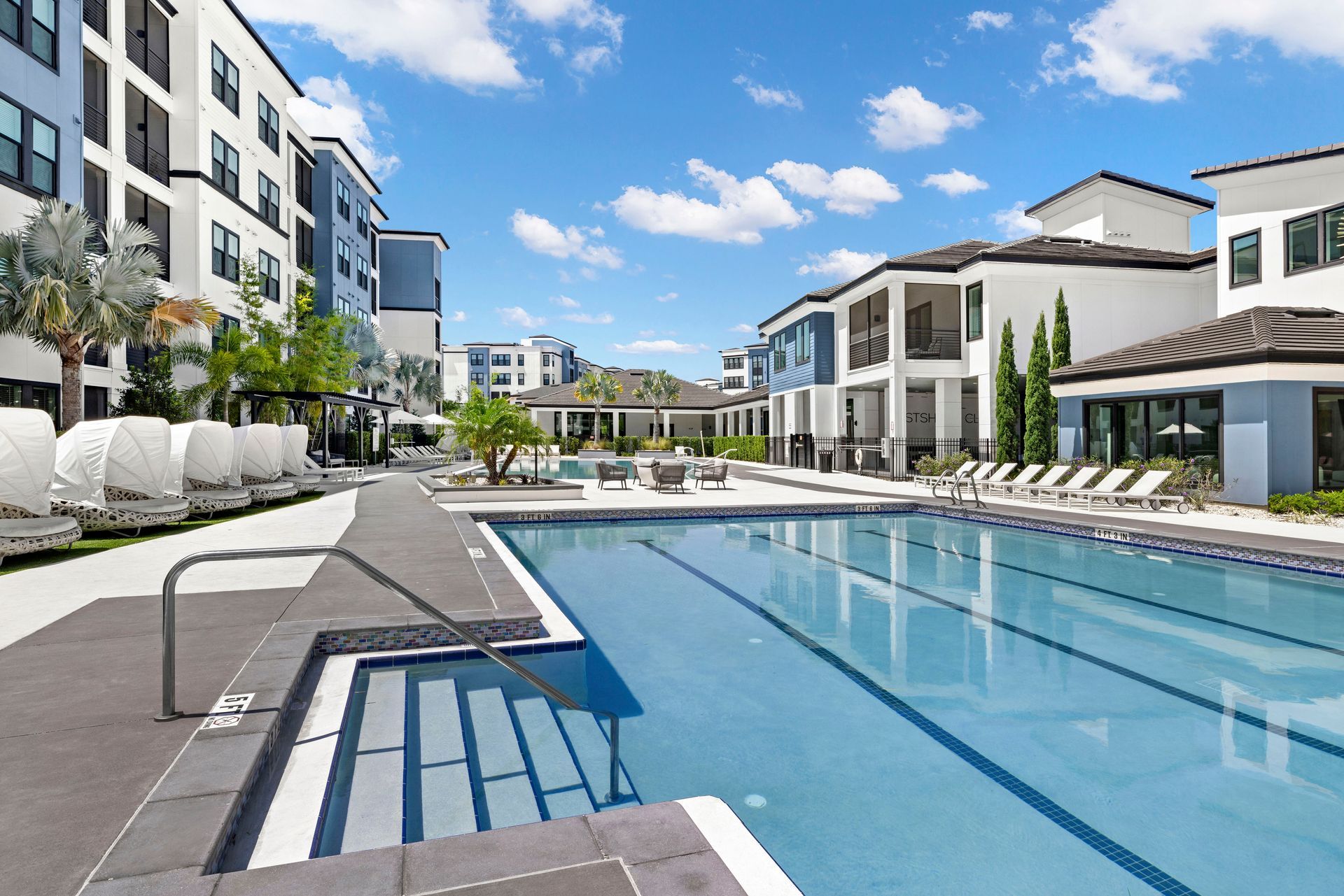 A large swimming pool in front of a large apartment building.