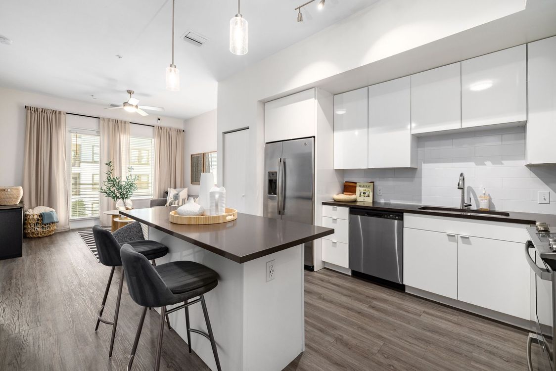 A kitchen with white cabinets and stainless steel appliances and a large island.