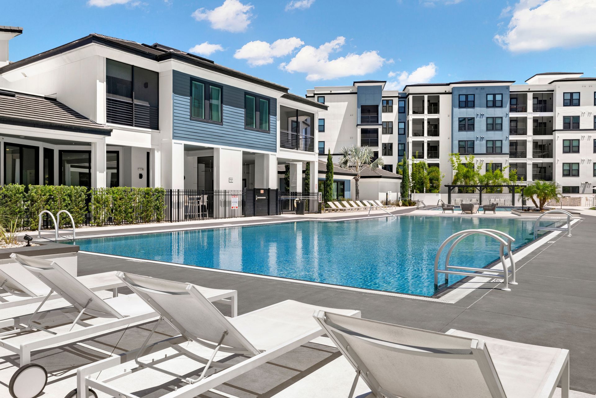 A large swimming pool in front of a large apartment building.