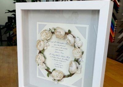 A white frame with a picture of a wreath of flowers on it.