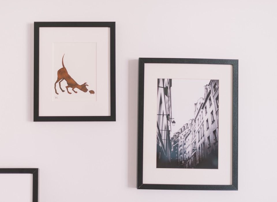 Three framed pictures are hanging on a white wall.