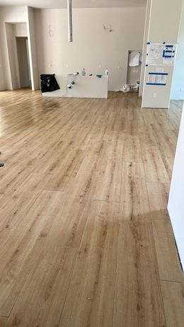 A large empty room with a wooden floor and white walls.
