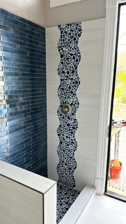 A bathroom with blue and white tiles and a window.