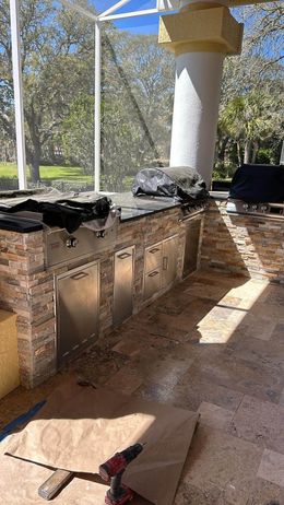 A large outdoor kitchen is being built on a patio.