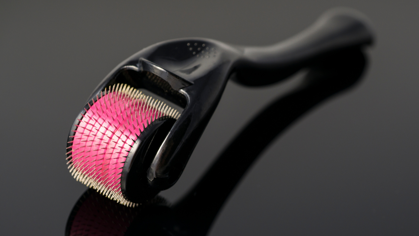 a close up of a roller with pink bristles on a black surface .