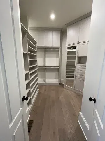 This walk-in closet stores a LOT and features drawers and a pull-out hamper, as well as a mirrored door.