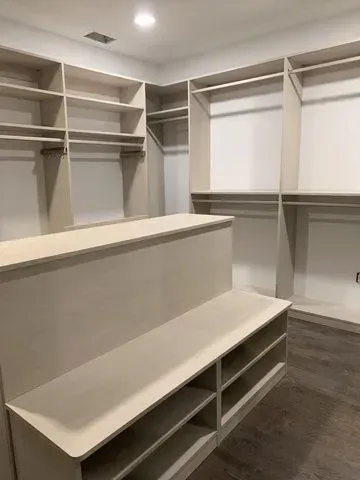 This walk-in closet features a bench with shoe storage.