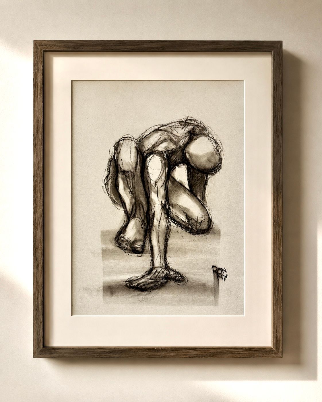 Framed black-and-white sketch of a crouching abstract human figure on a beige wall