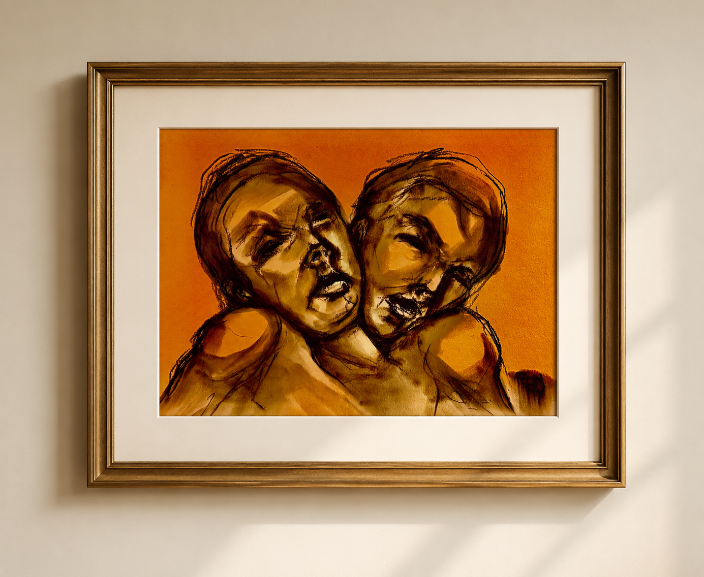 Framed abstract artwork with two warm-toned, overlapping faces on a white wall