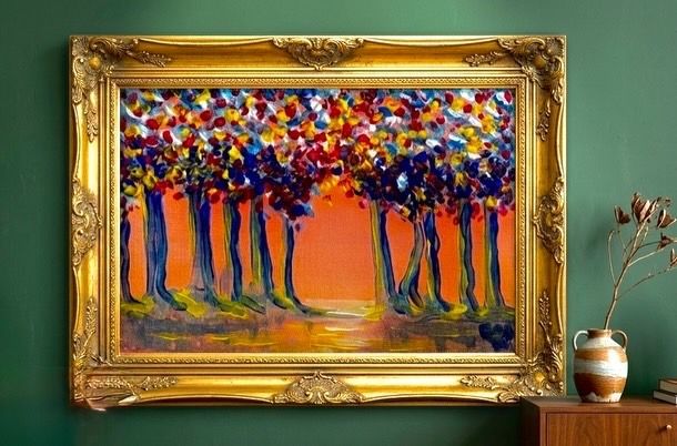 Framed colorful abstract forest painting on a green wall beside a small vase on a table