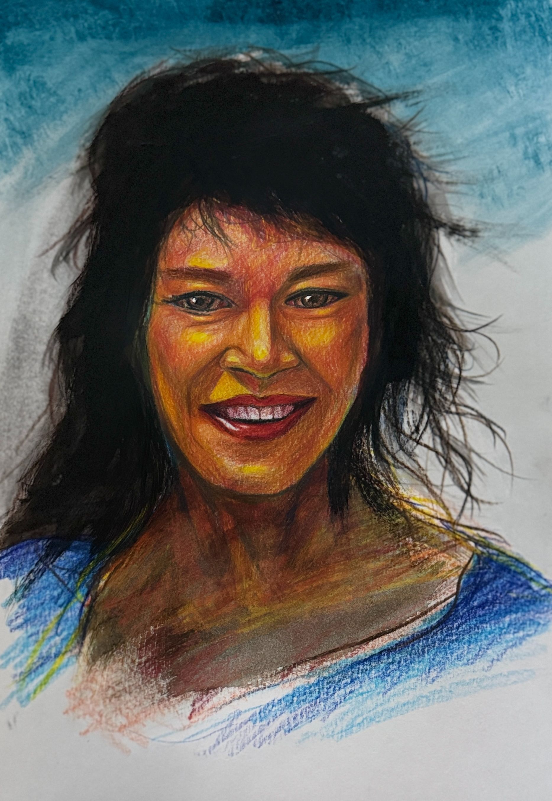 Portret van een lachend persoon met donker haar en een warm getinte huid tegen een blauwe achtergrond.