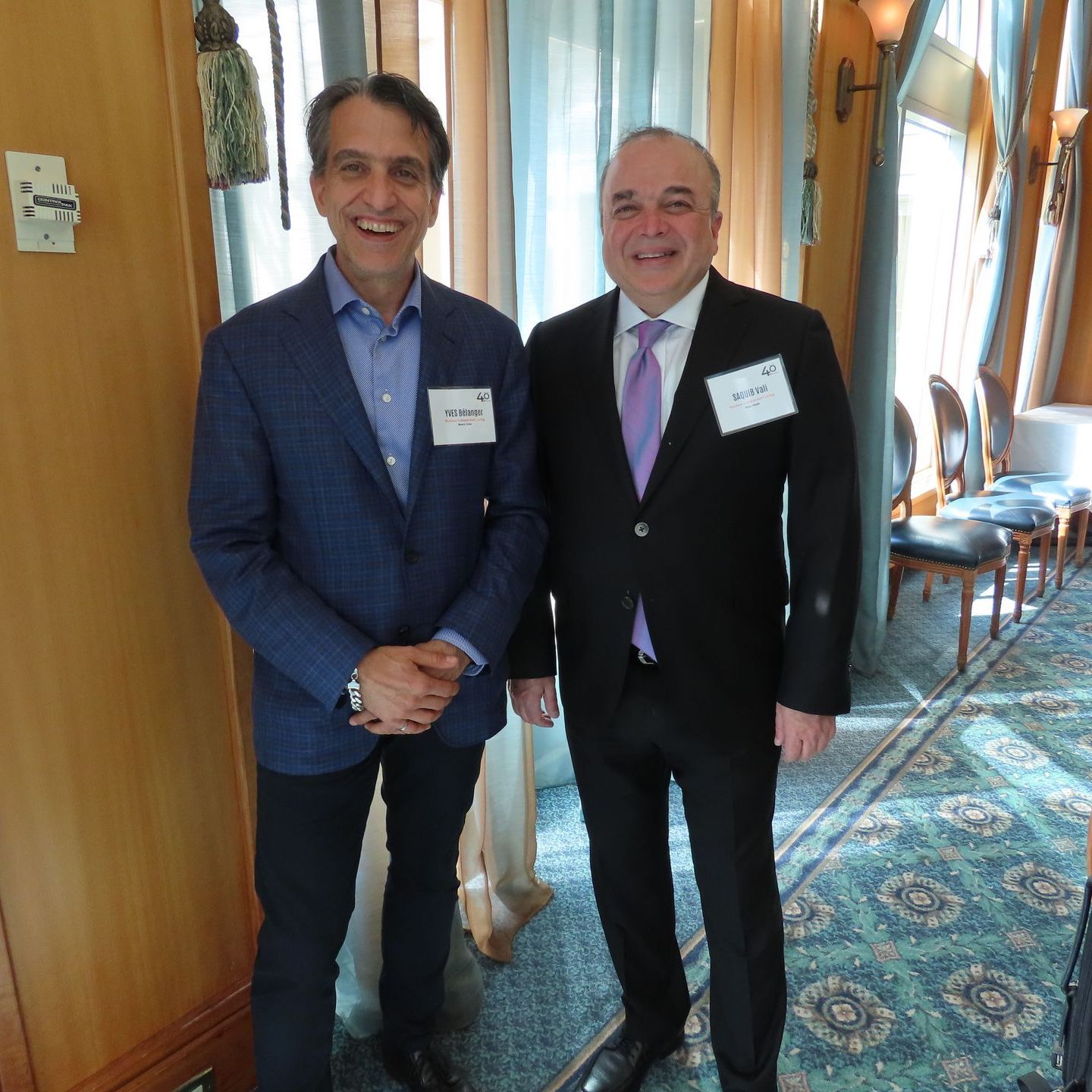 Two men standing next to each other with one wearing a name tag