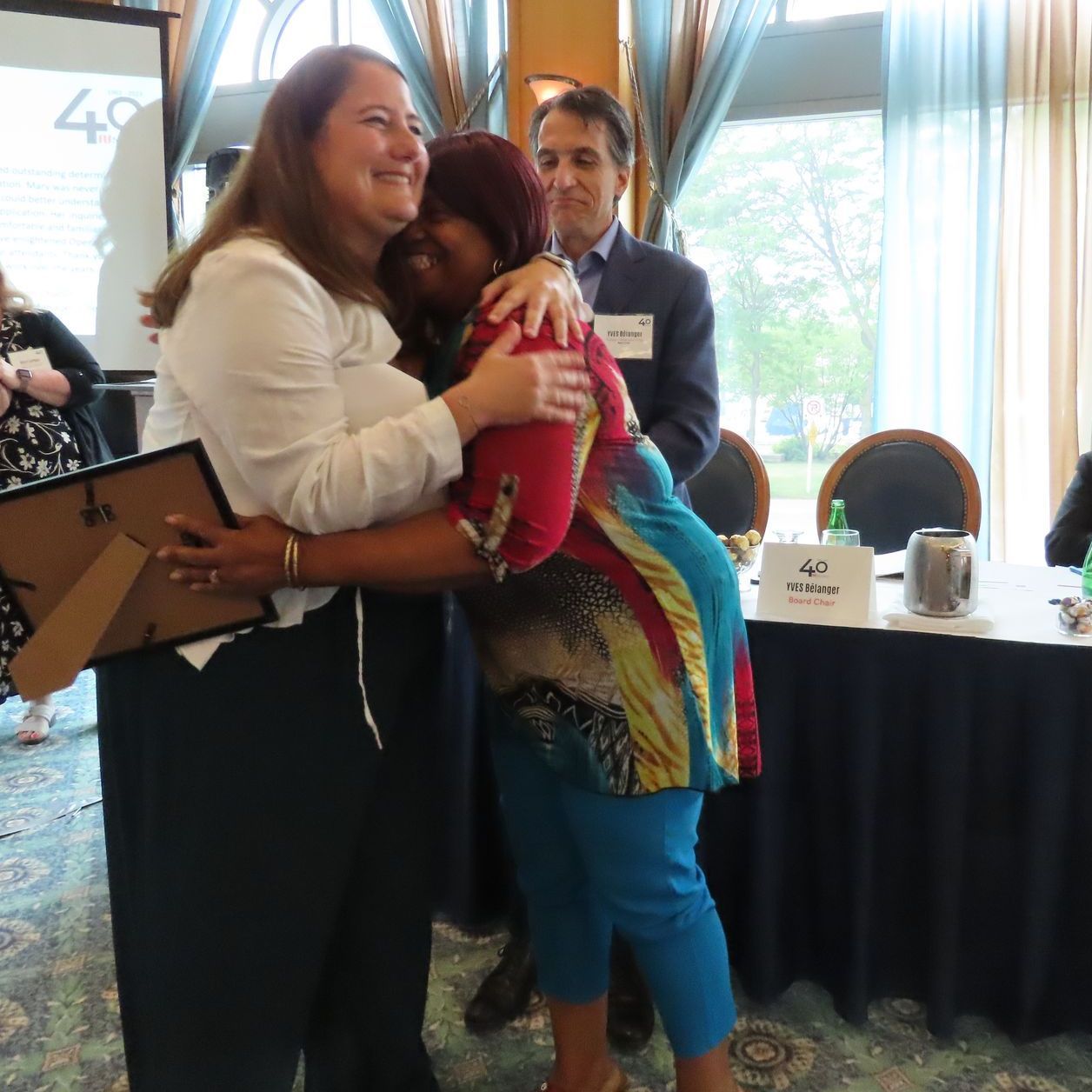 A woman hugging another woman in front of a sign that says 49
