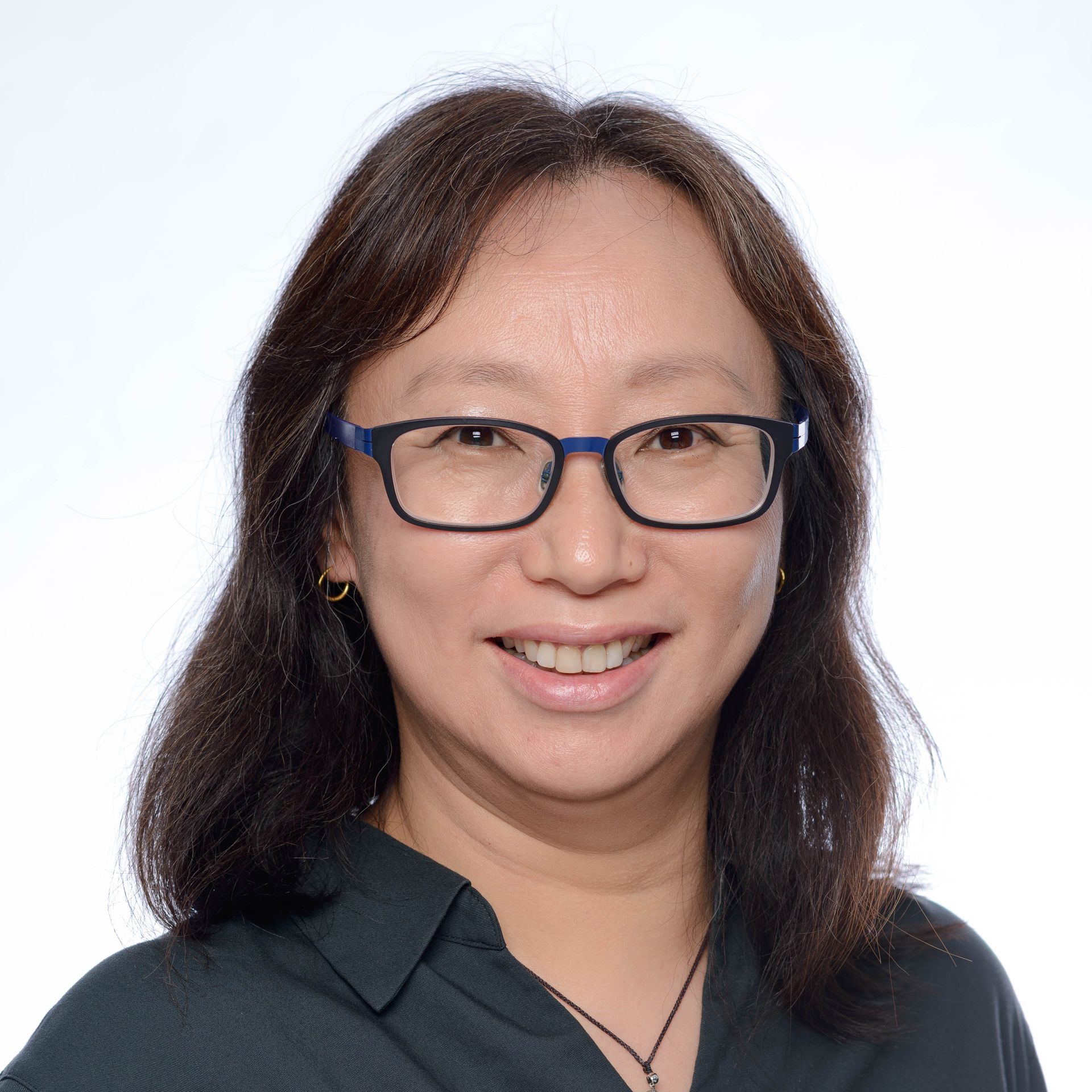 A woman wearing glasses and a polka dot shirt is smiling for the camera.
