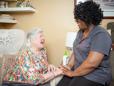 A nurse is holding the hand of an elderly woman in a living room.
