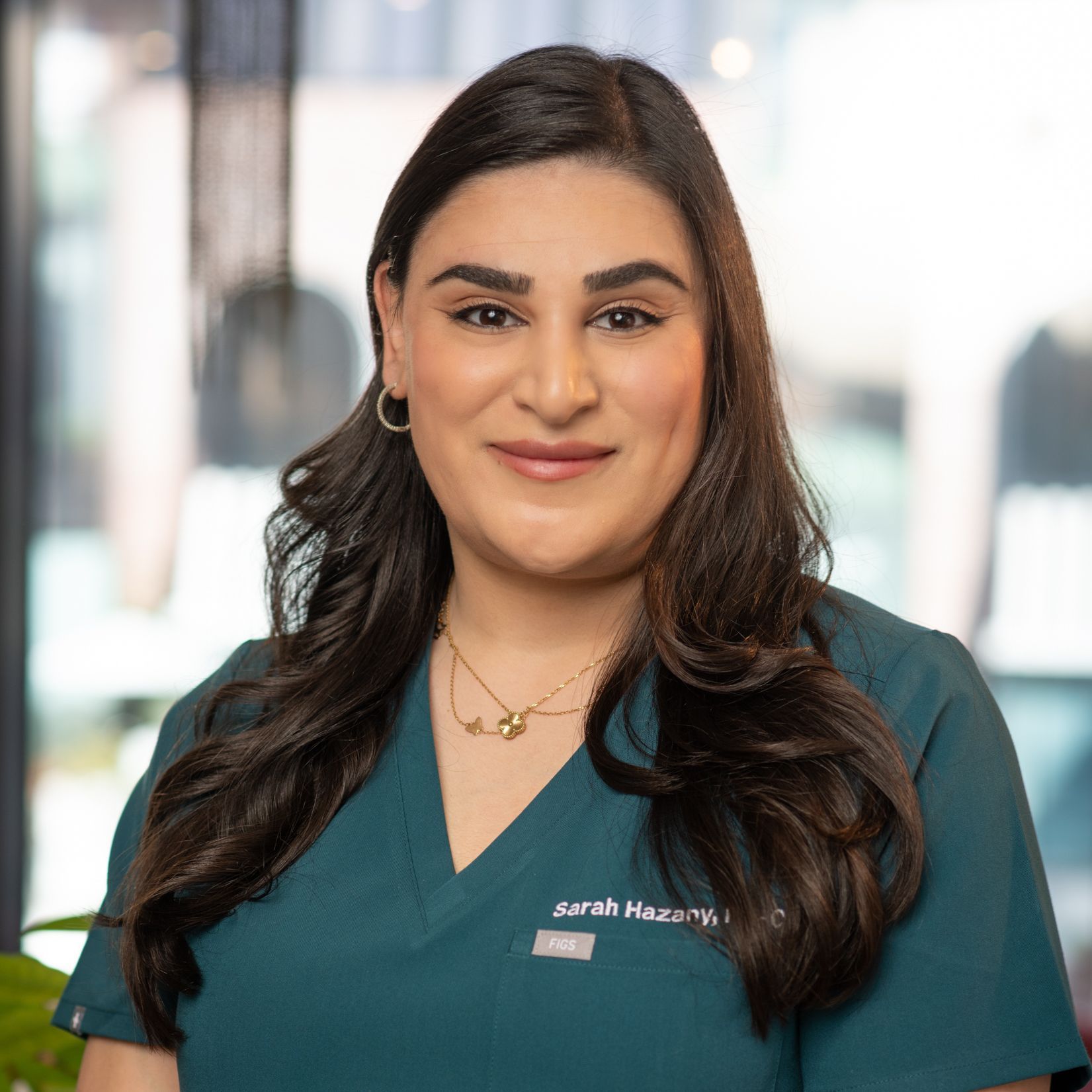 A woman in green scrubs is smiling