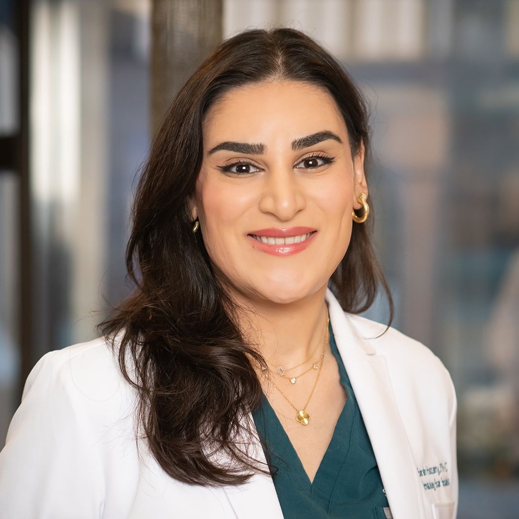 A woman in green scrubs is smiling