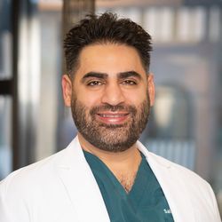 A woman in green scrubs is smiling