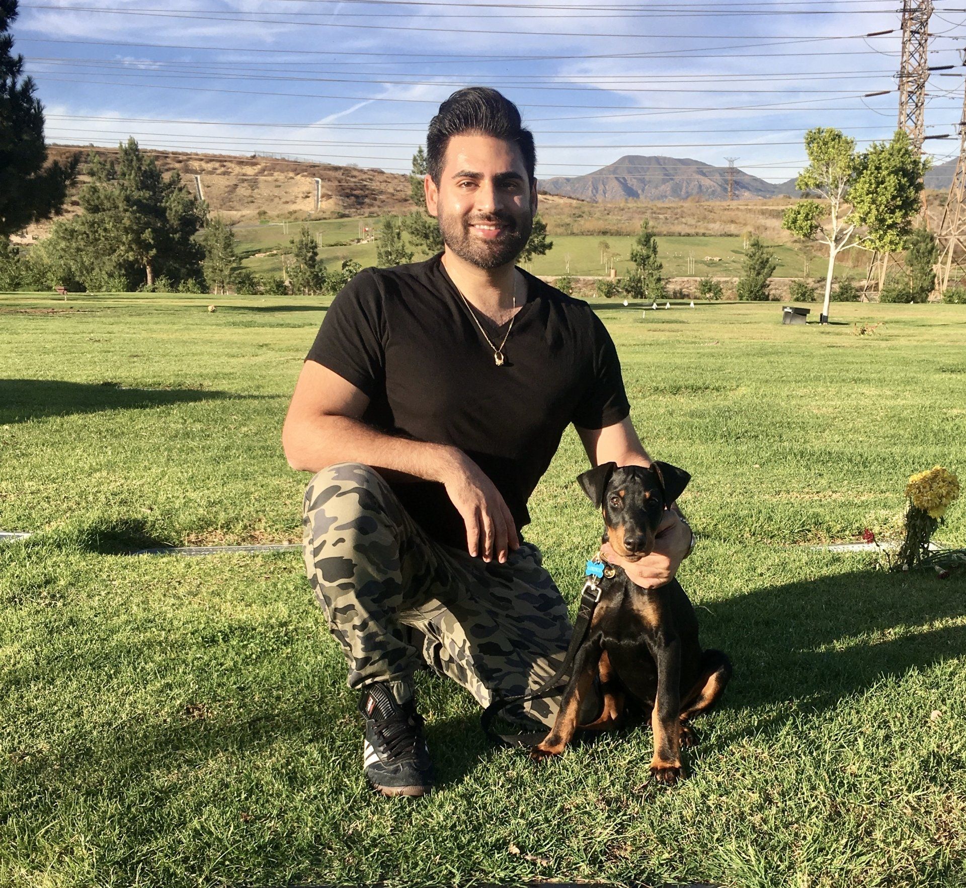 A man is kneeling down next to a dog in a field