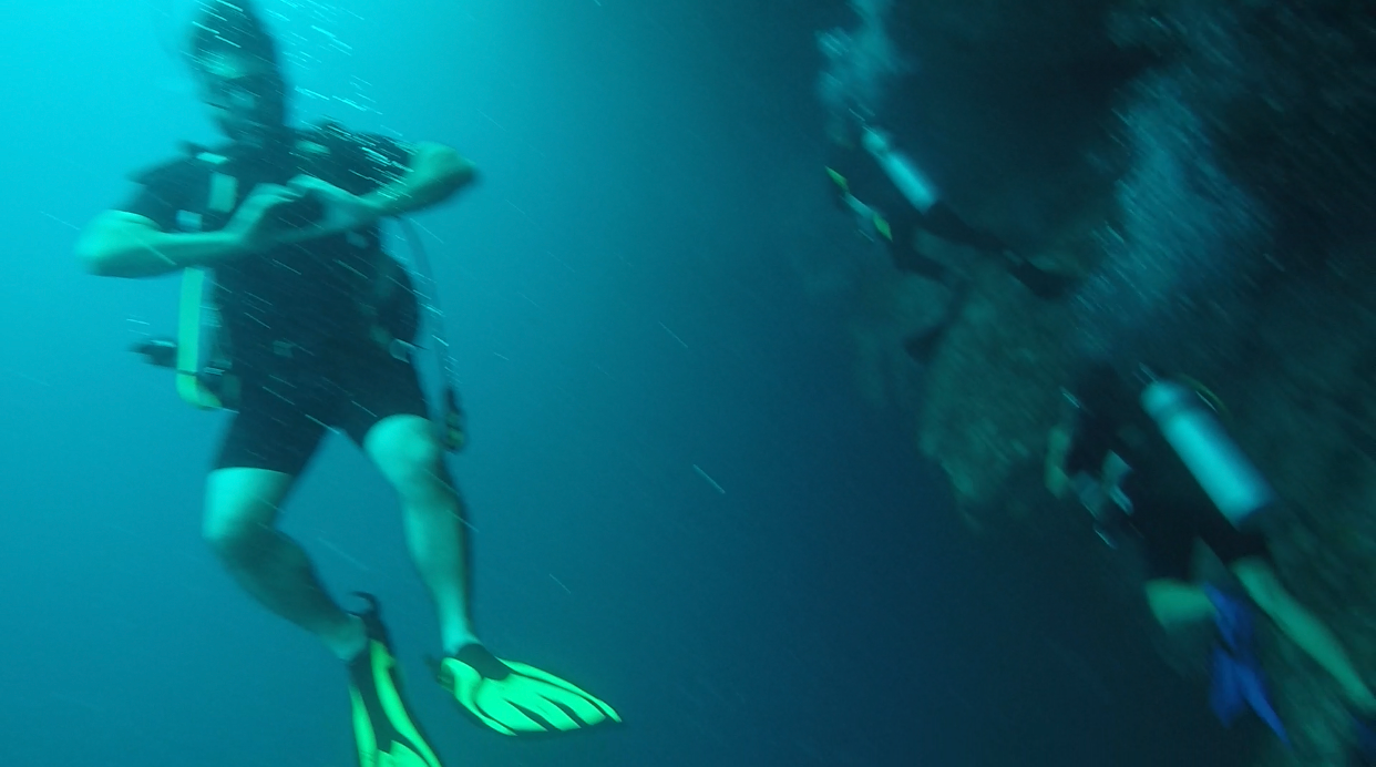 A man is making a heart shape with his hands while scuba diving in the ocean.