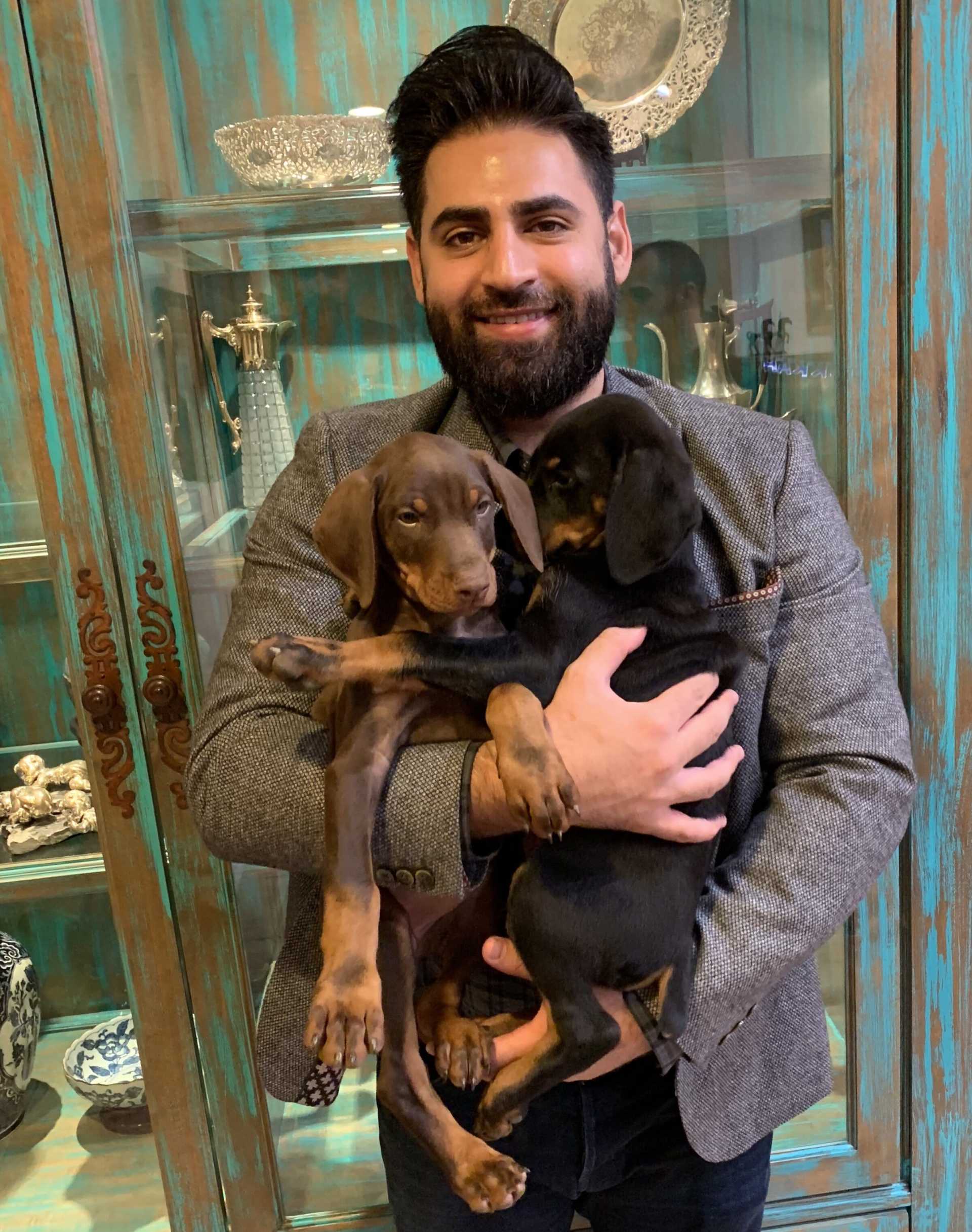 A man is holding two puppies in his arms.