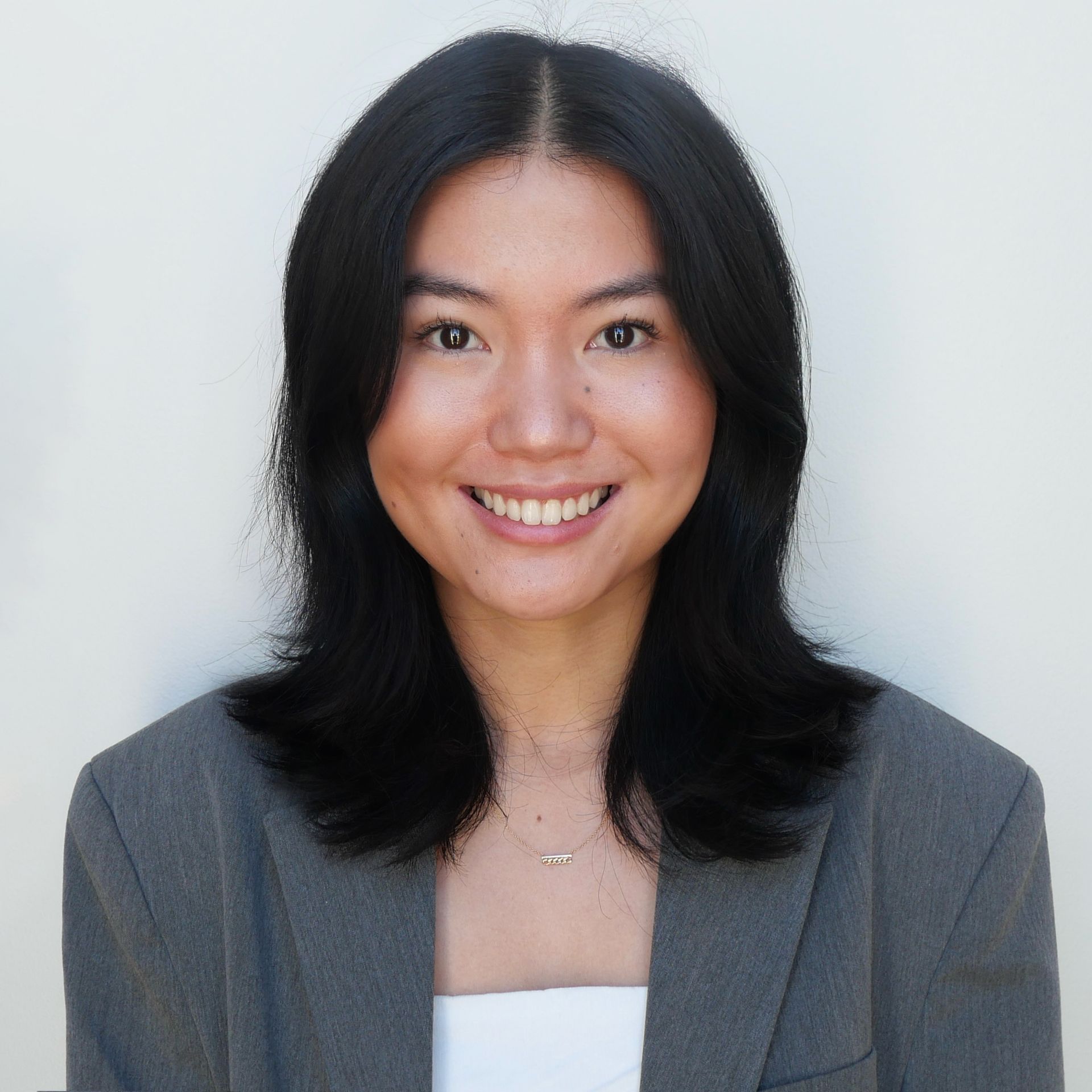 A woman in a black jacket and white shirt is standing in a hallway.