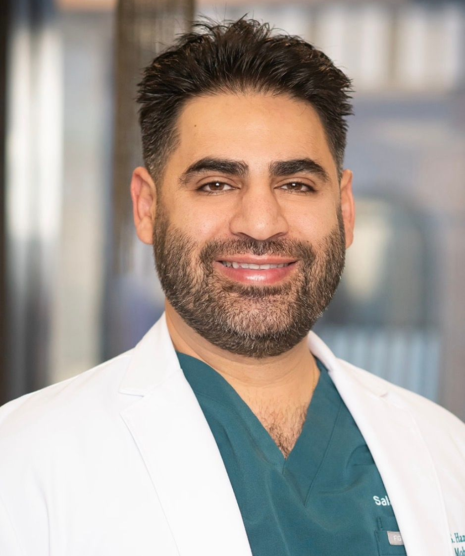 A woman in green scrubs is smiling