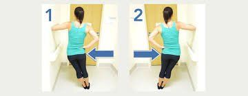 A woman in a blue tank top is standing in front of a door.