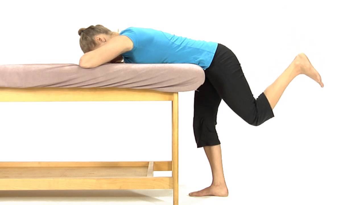 A woman in a blue shirt is doing exercises on a massage table.