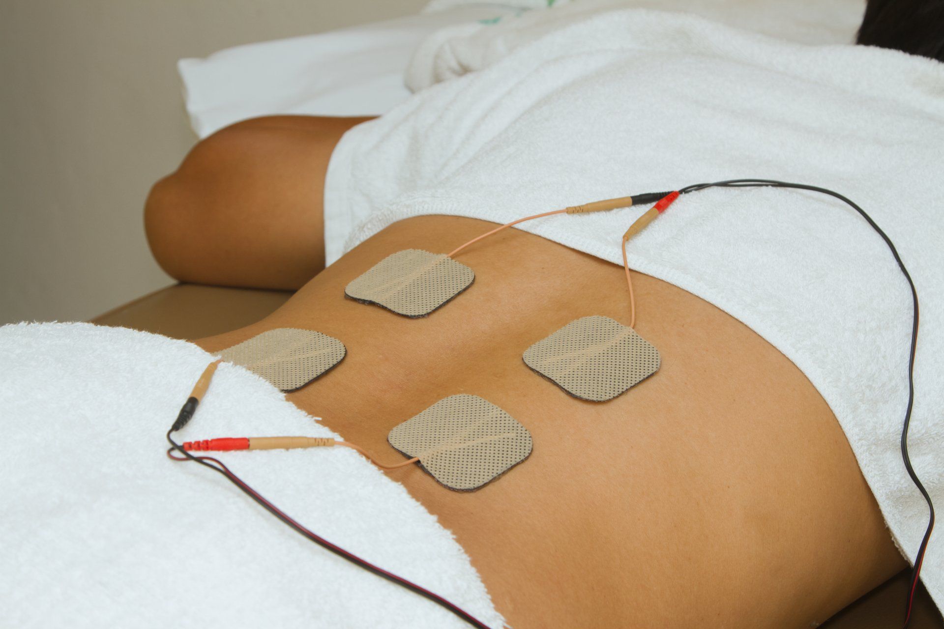 A woman is laying on a table with electrodes on her back