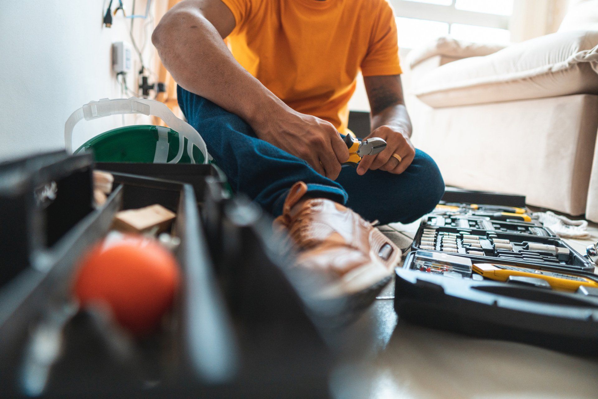 Un idraulico è seduto sul pavimento con una cassetta degli attrezzi.