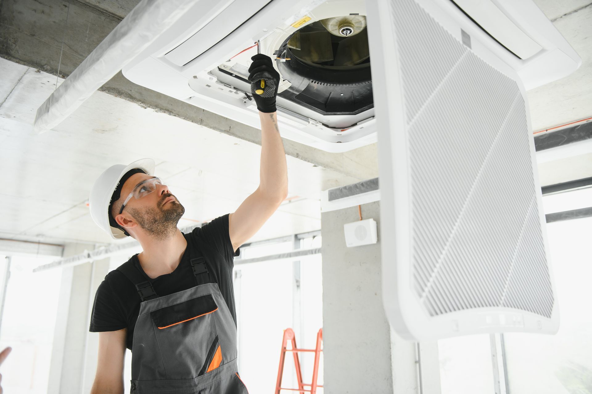A man is working on a ceiling fan in a building.