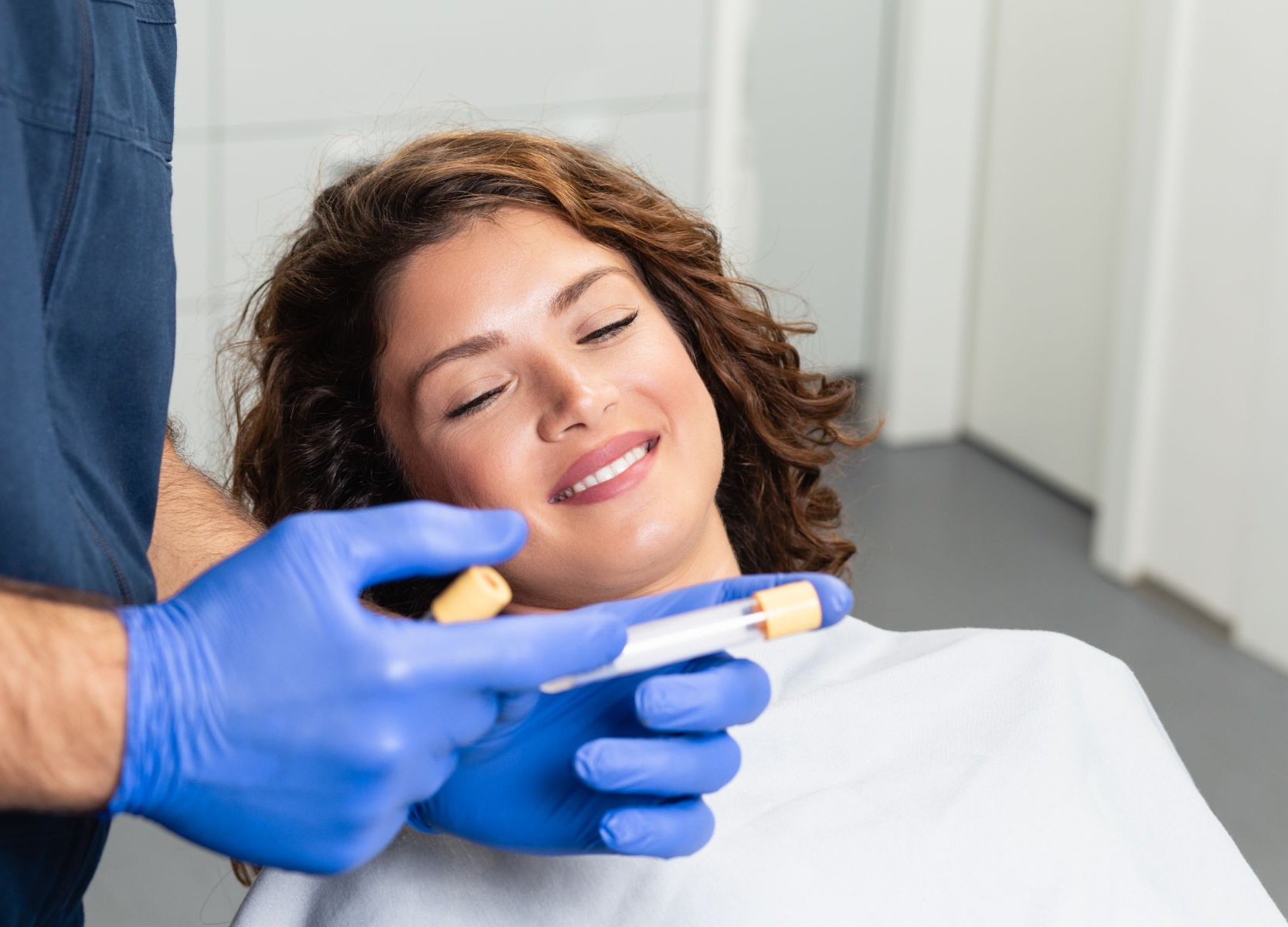 doctor explains blood sample to female patient in exam chair