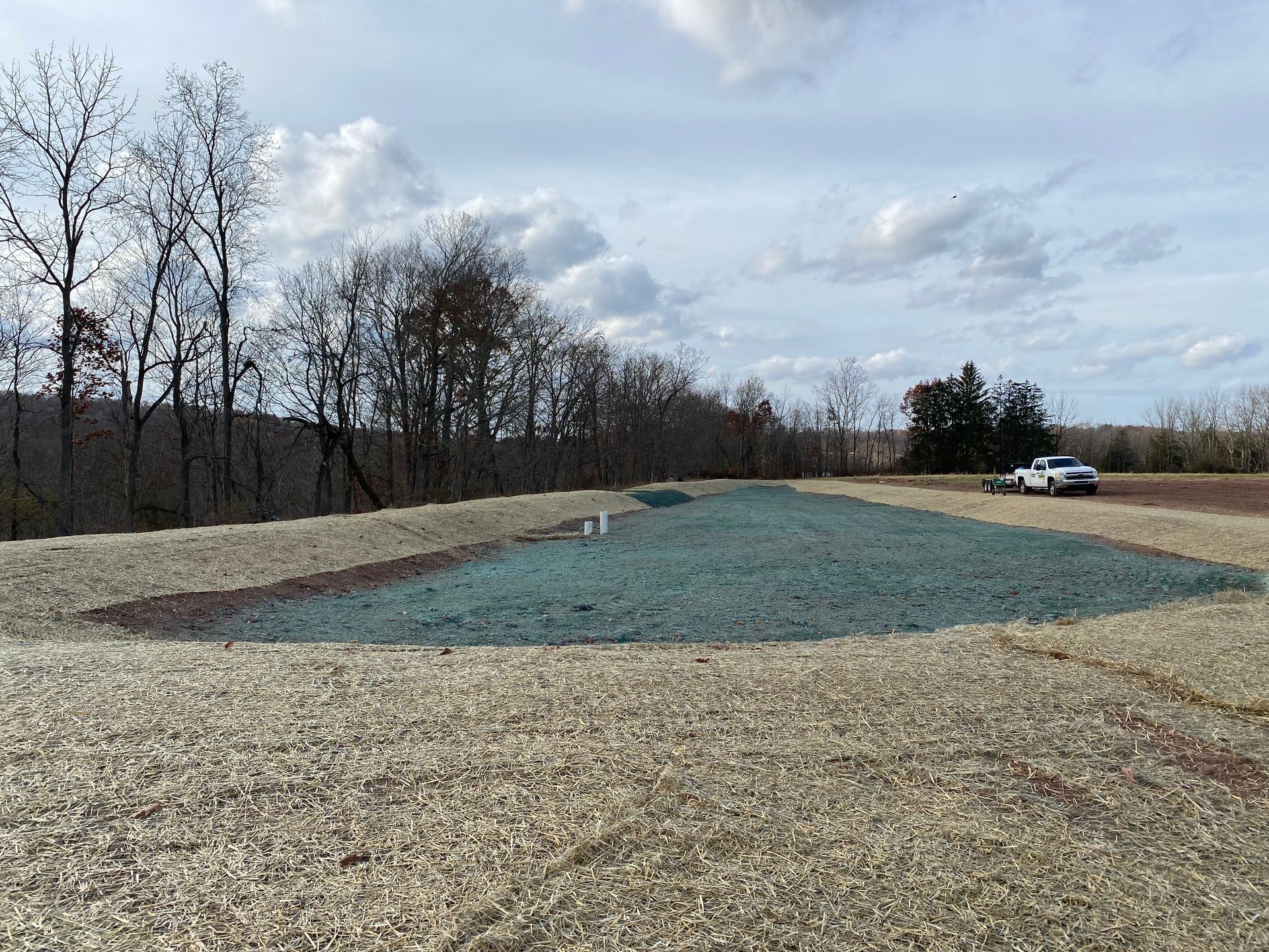 A gravel road with trees in the background and a truck parked in the background.