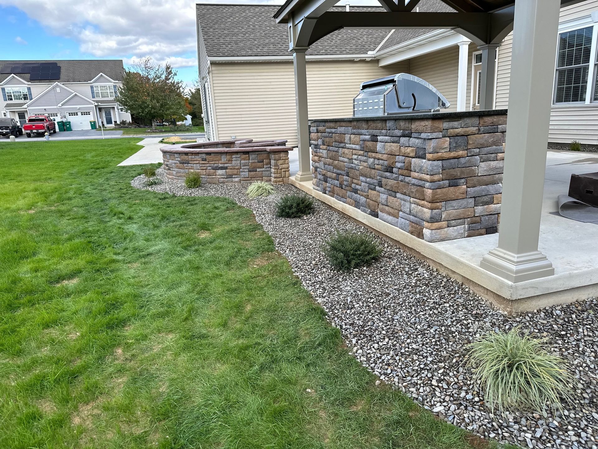 Backyard patio with stacked stone structures, gazebo, and green lawn.