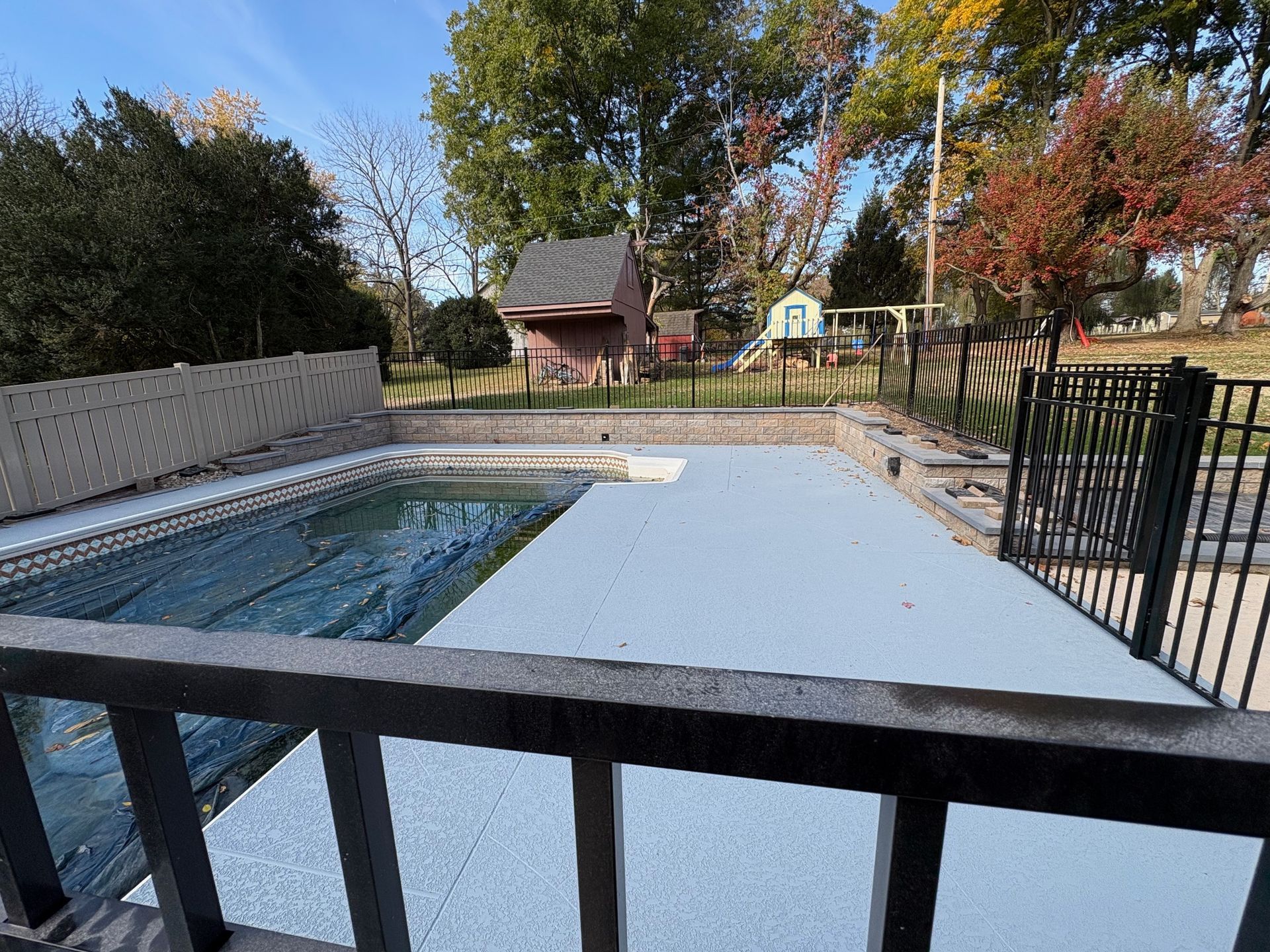 A large swimming pool is surrounded by trees and a fence installed by complete property solutions of Lancaster PA