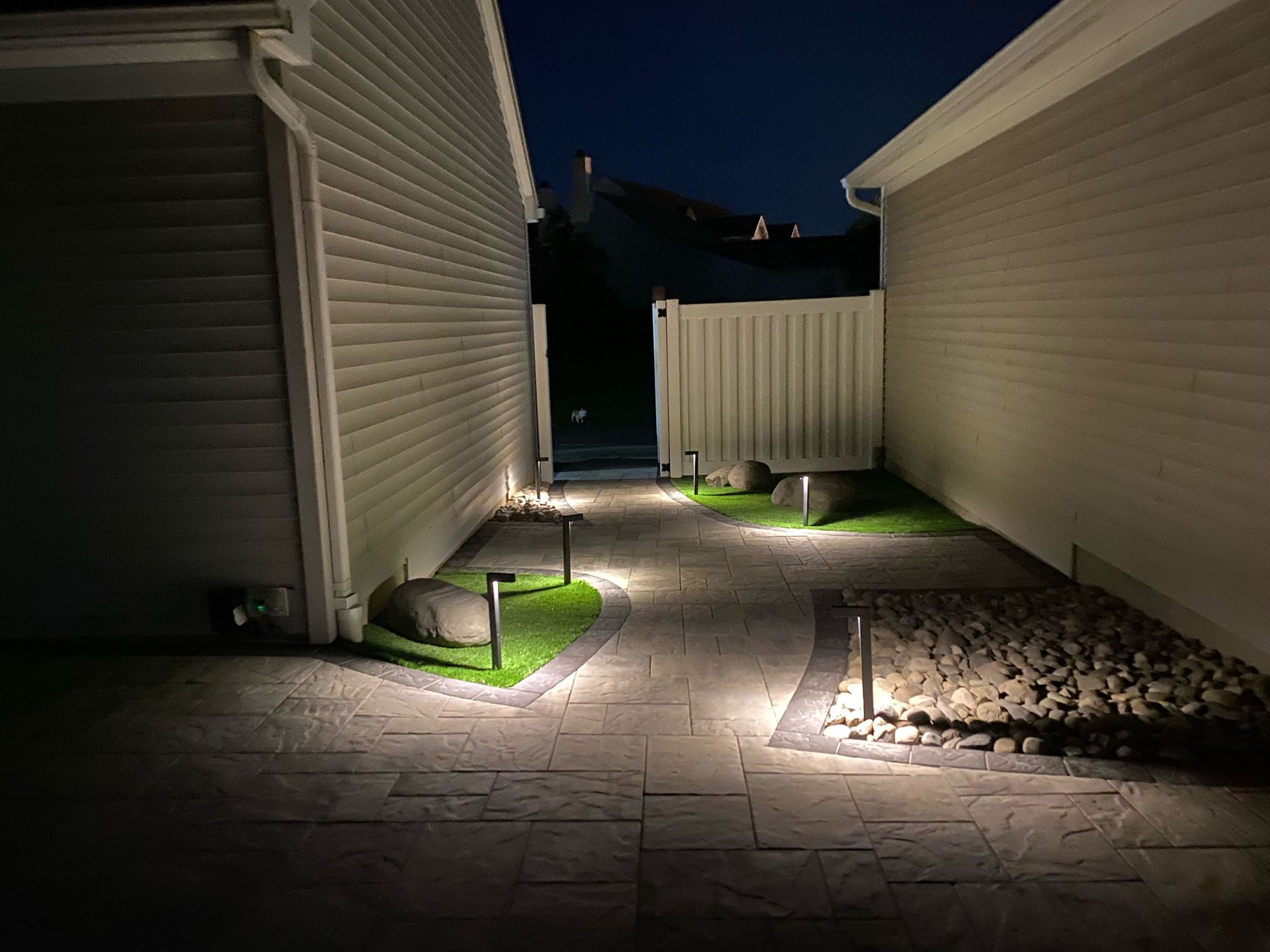 A walkway between two houses is lit up at night installed by complete property solutions of Lancaster PA