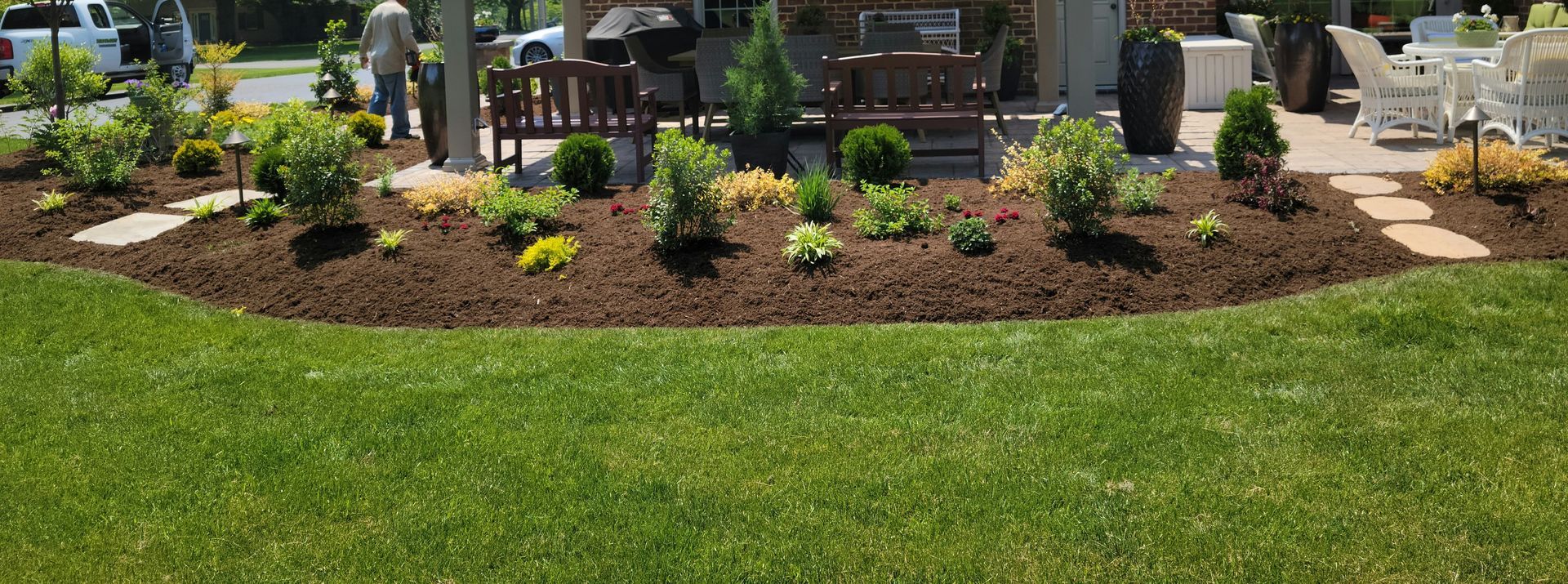 A lush green lawn with a patio and a bench in the background installed by complete property solutions of Lancaster PA