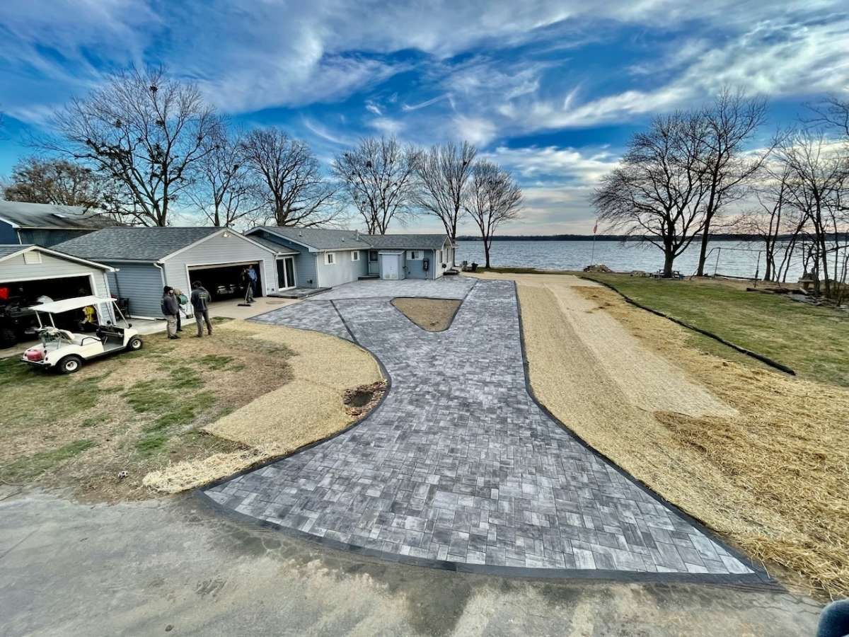 New paver driveway leading to a house next to a lake installed by complete property solutions of Lancaster PA