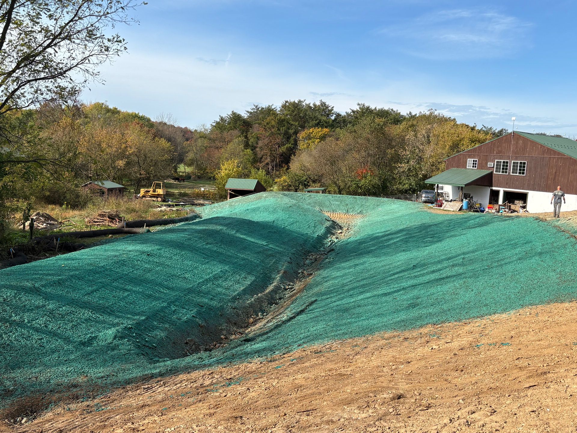 A newly seeded lawn covered with green netting, next to a white garage.