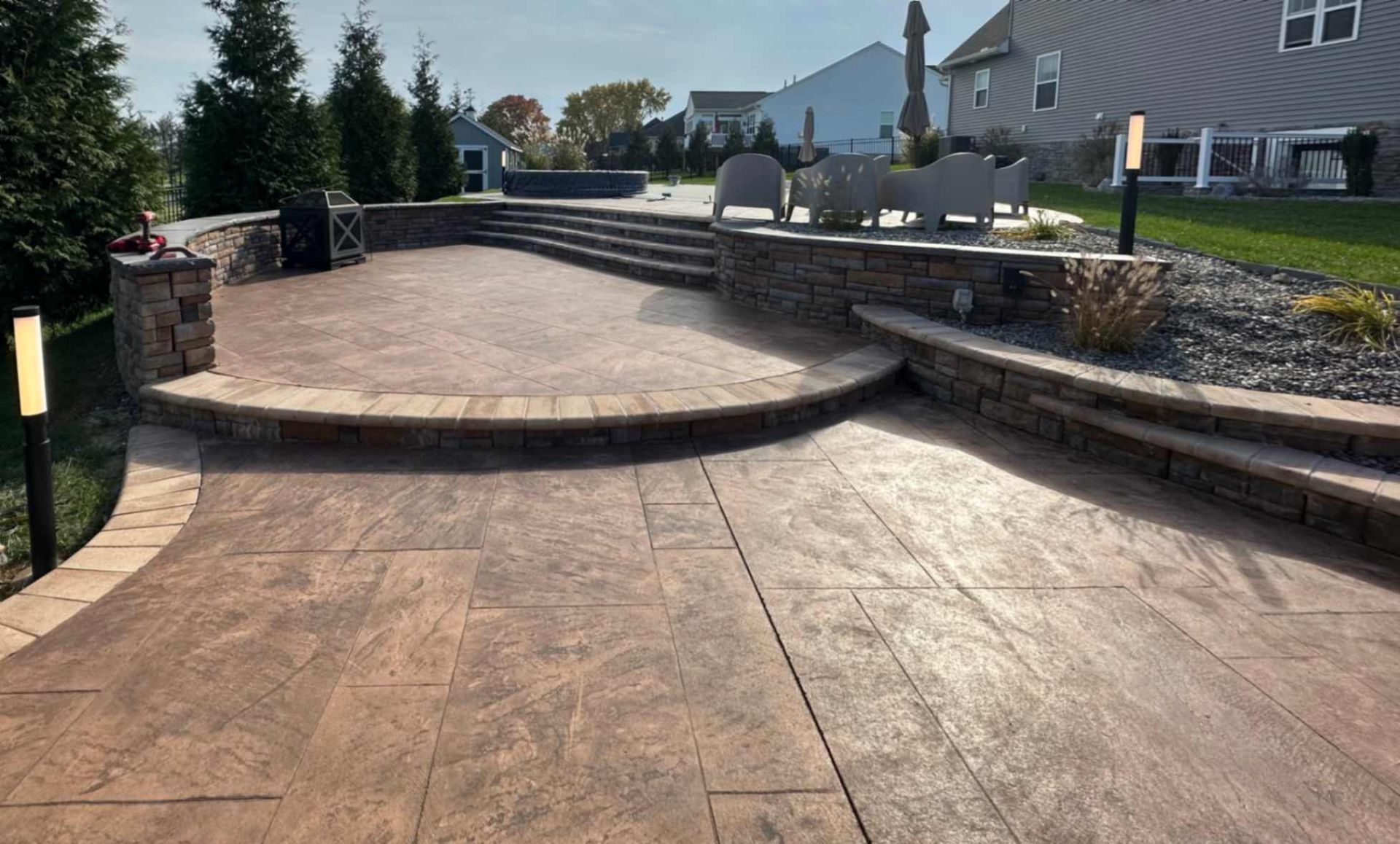 Outdoor patio with stamped concrete, retaining walls, steps, and lighting.